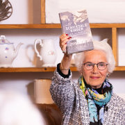 "Mauthausen-Baby" Eva Clarke bei der Buchpräsentation © MKÖ/Alissar Najjar Eva Clarke hält das Buch "Schicksalskinder – Die KZ-Babys von Mauthausen" in die Höhe.